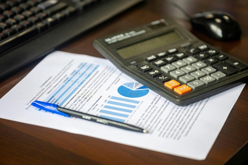 pexels-photo-33175667-33175667 Desk with calculator, financial report, and pen, suggesting business analysis.